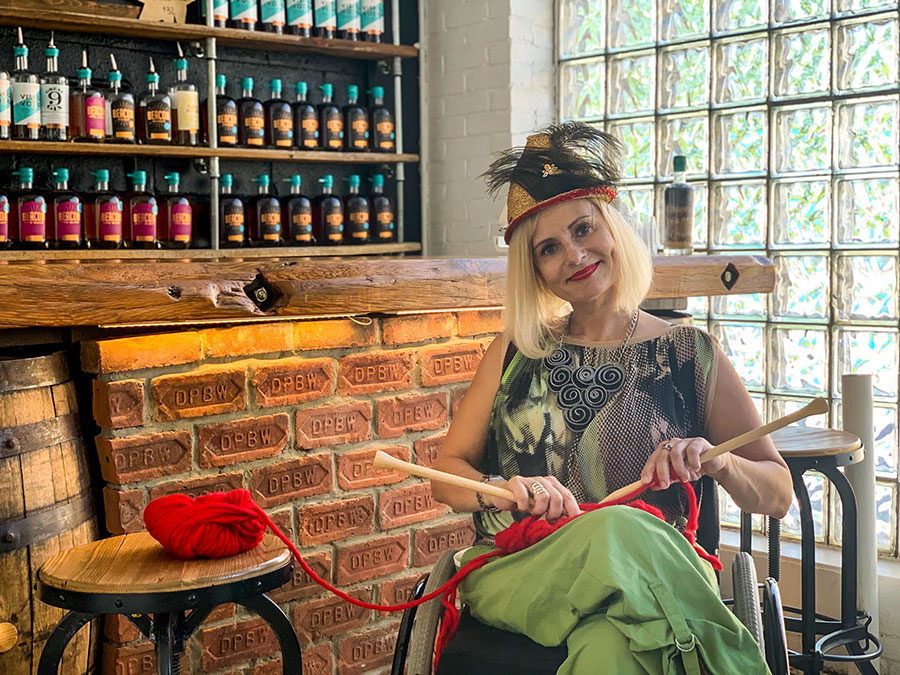Wheelchair fashion blogger knitting in distillery